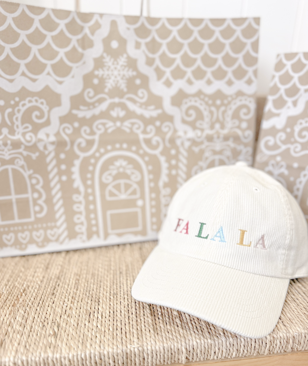White cap with 'FA LA LA' text on a textured surface with decorative background