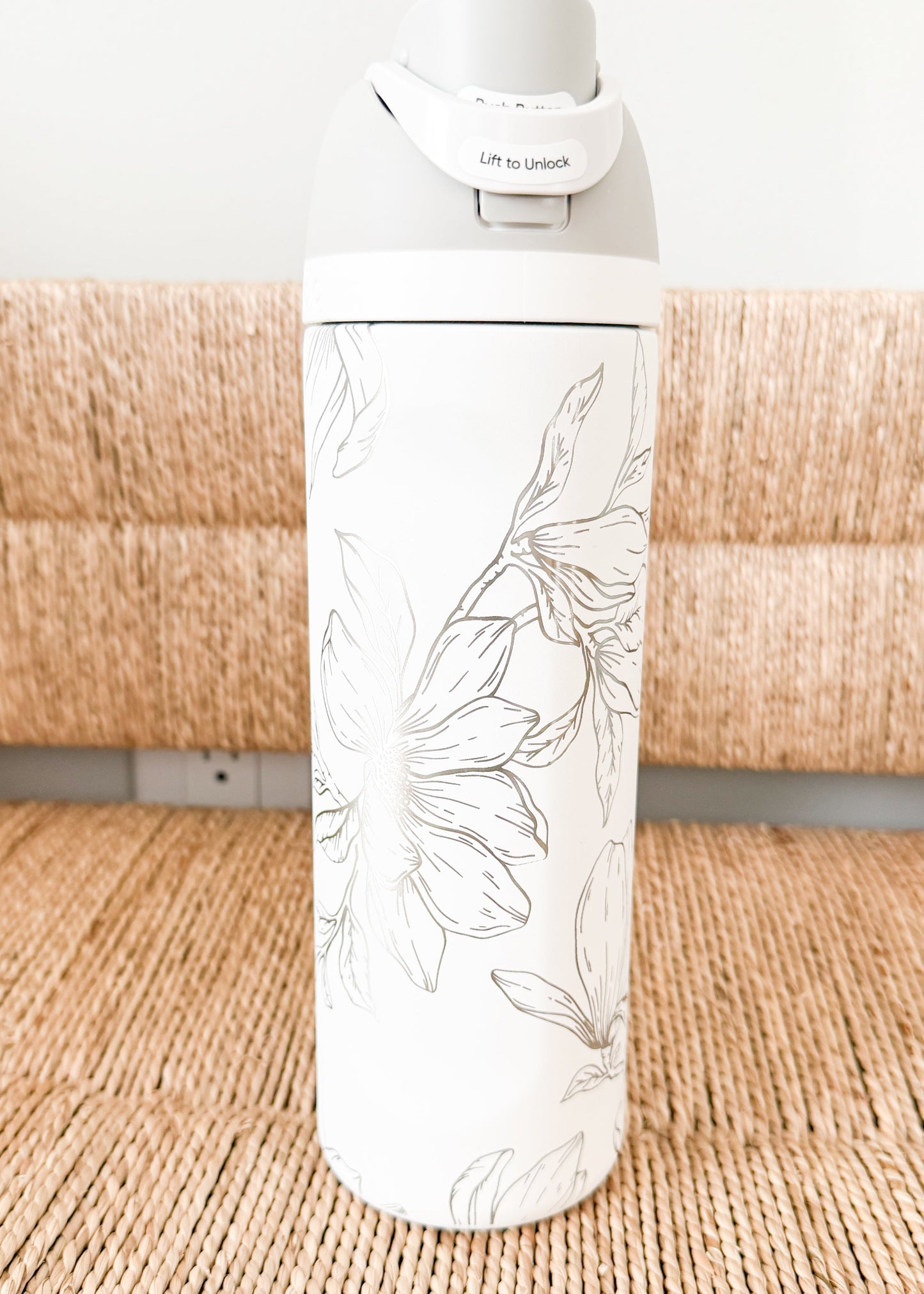 White water bottle with floral design on a woven surface