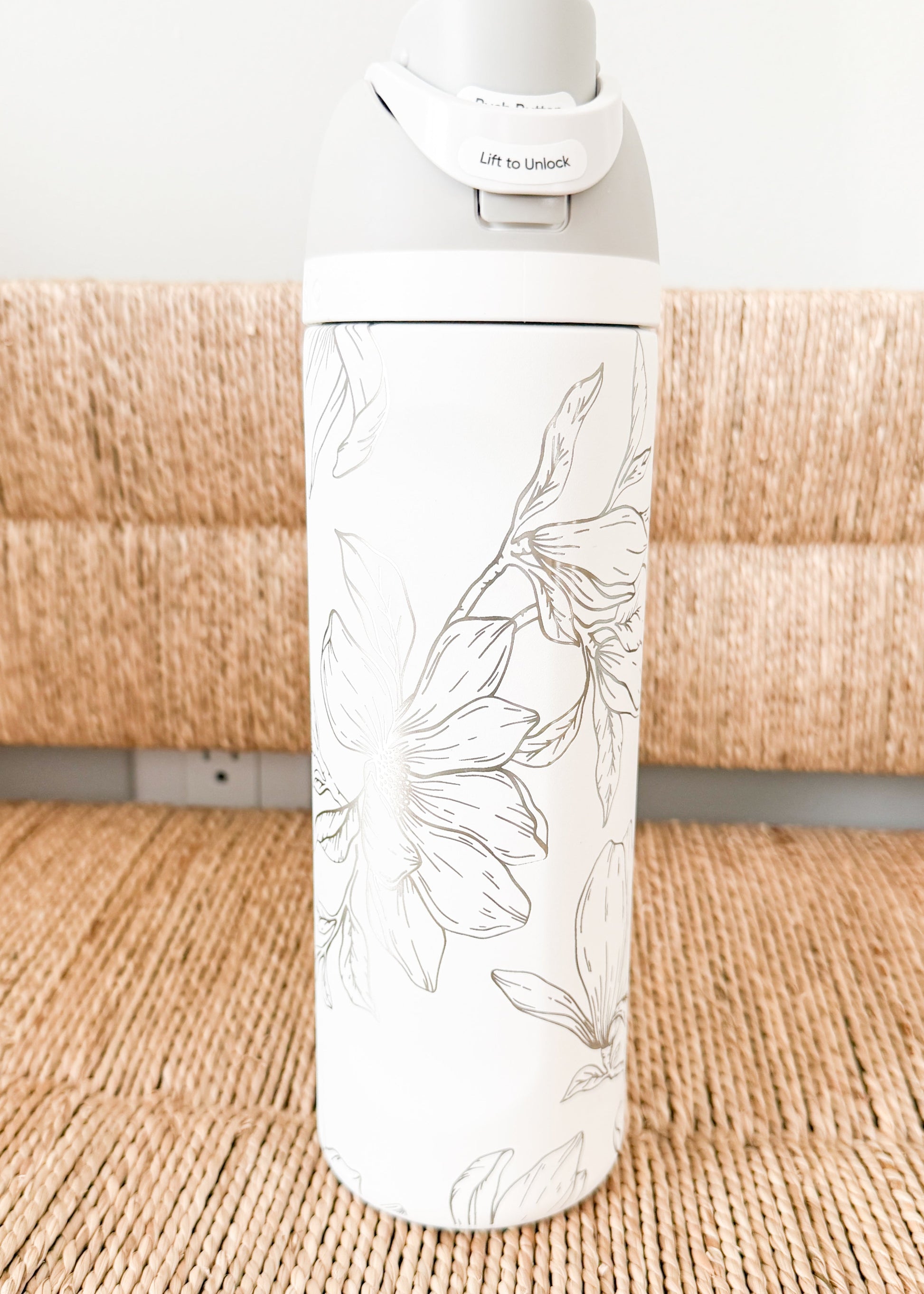 White water bottle with floral design on a woven surface