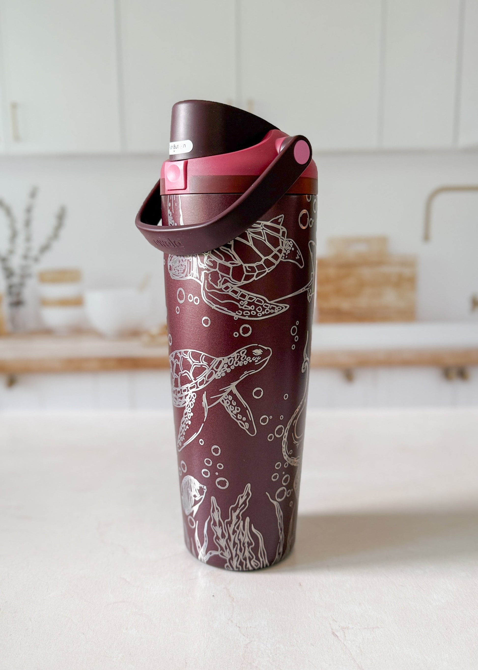 Maroon tumbler with design on a white surface